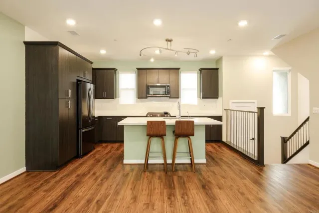 a kitchen with stainless steel appliances kitchen island granite countertop a sink refrigerator and microwave