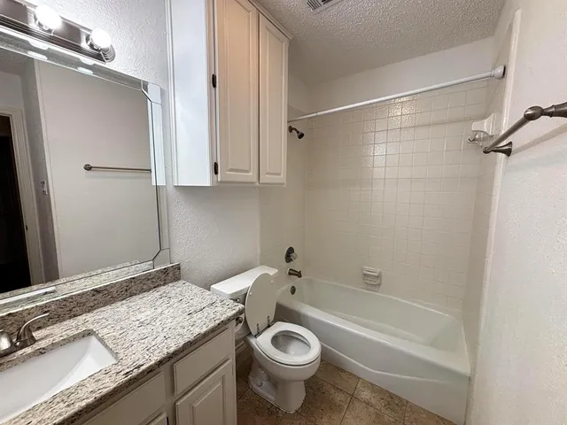 a bathroom with a granite countertop sink a toilet and shower