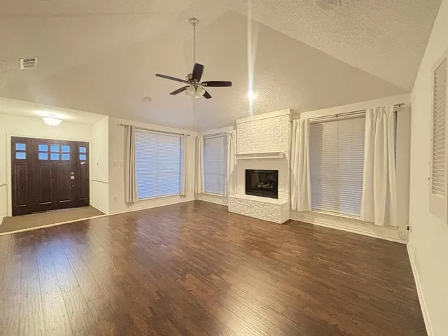 a view of empty room with wooden floor and fireplace