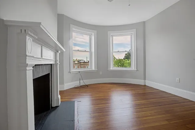 an empty room with windows a fireplace and wooden floor
