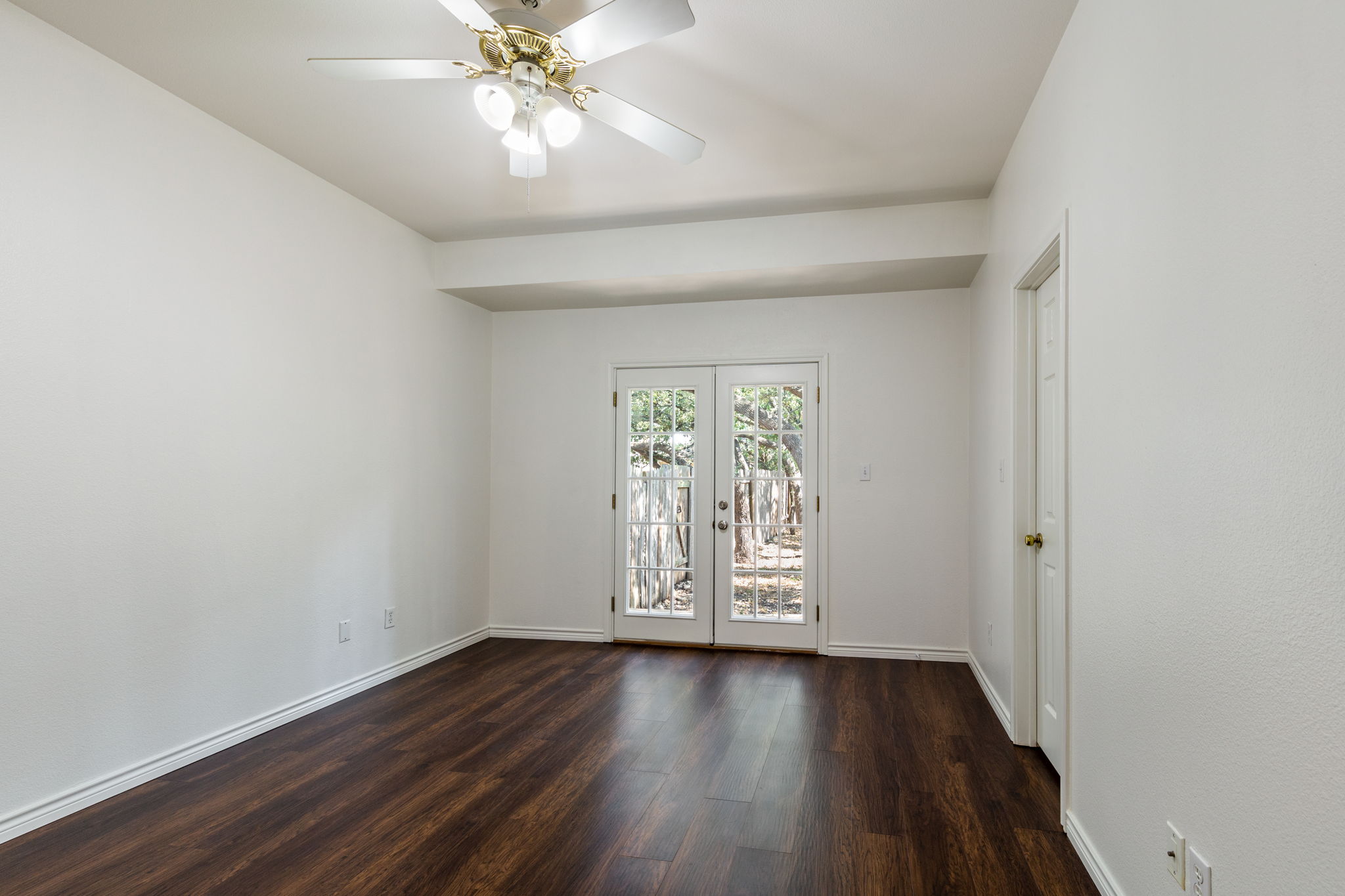 8708 Weiser Drive, Unit B Austin, TX 78729 - Photo 14 of 30 an empty room with wooden floor chandelier fan and windows