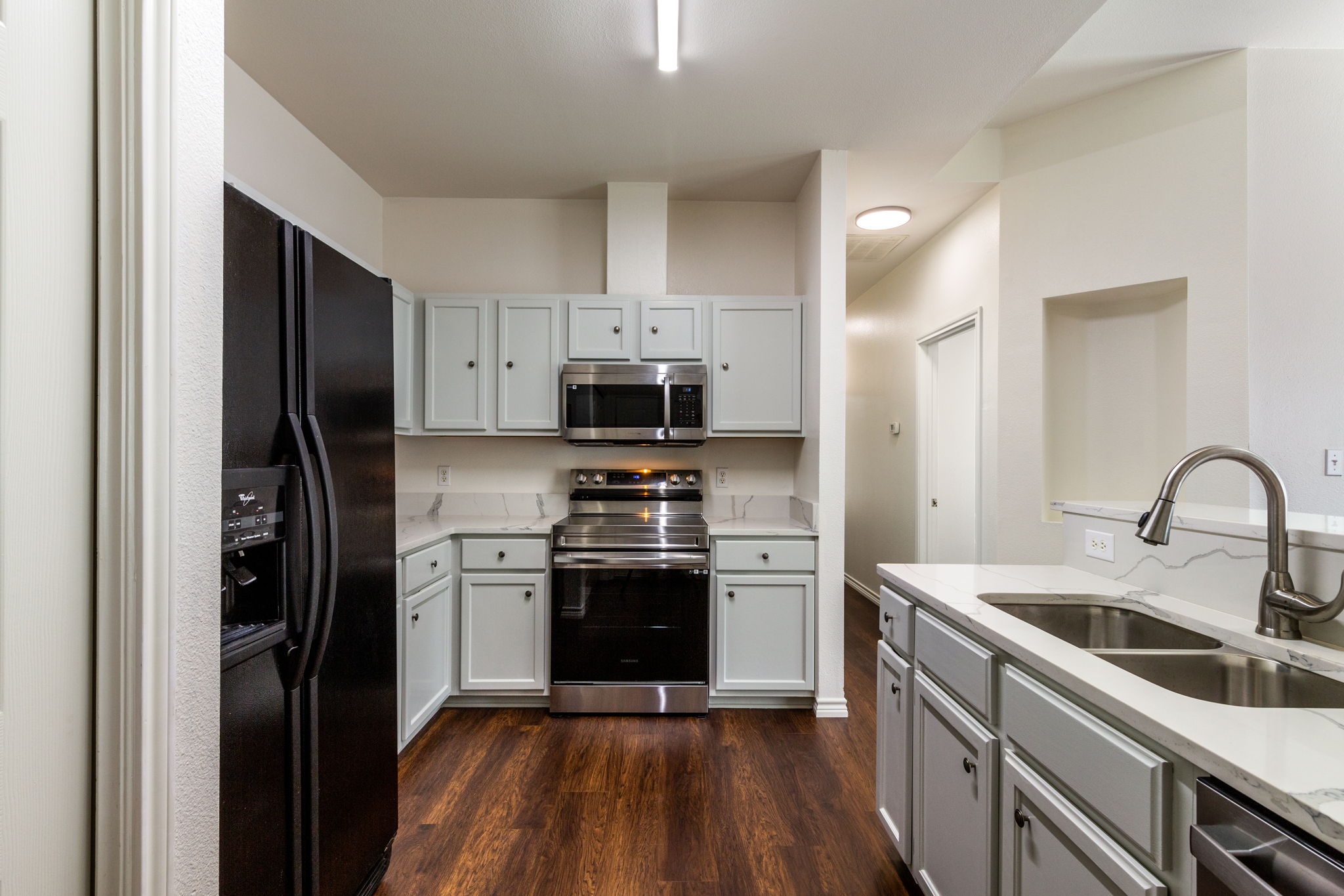 8708 Weiser Drive, Unit B Austin, TX 78729 - Photo 2 of 30 a kitchen with stainless steel appliances granite countertop a refrigerator a stove top oven a sink and dishwasher with wooden floor