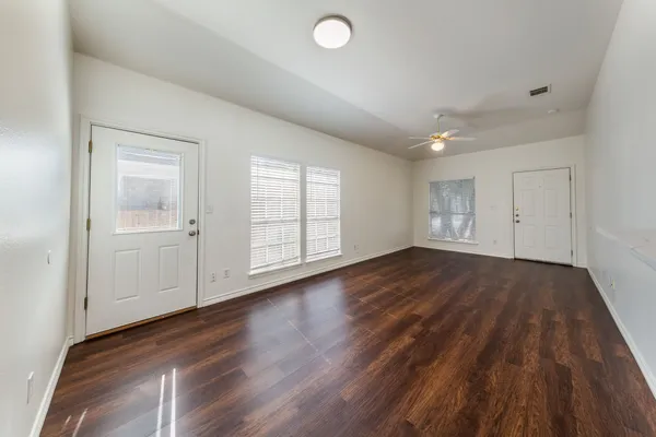 an empty room with wooden floor and windows