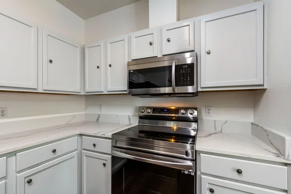 a kitchen with stainless steel appliances white cabinets and a stove top oven