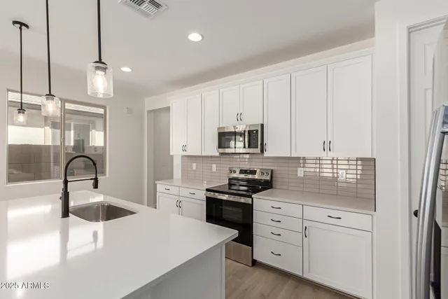 a kitchen with white cabinets and sink