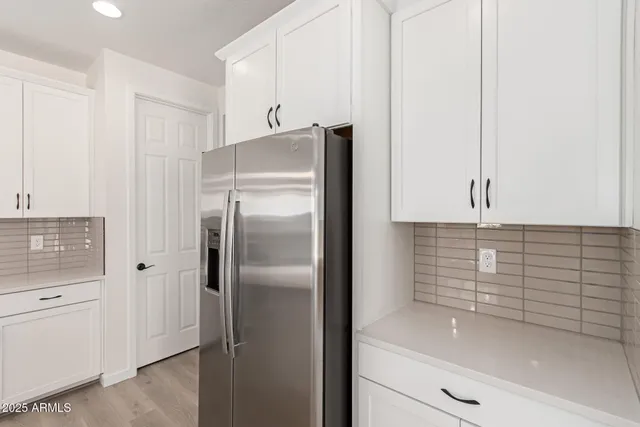a kitchen with white cabinets stainless steel appliances and wooden floor