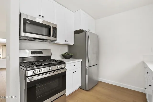 a kitchen with stainless steel appliances white cabinets a stove a microwave and a refrigerator