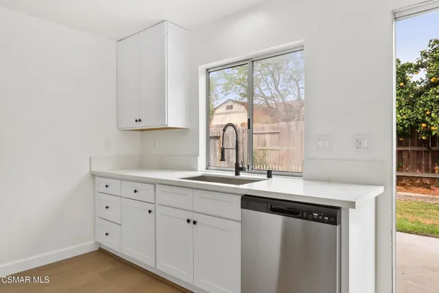 a kitchen with white cabinets and a window