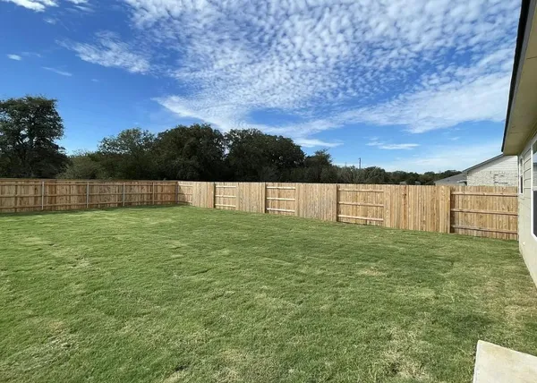 a view of yard with grass and a fence