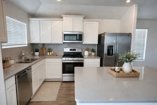 a kitchen with stainless steel appliances a sink stove refrigerator and cabinets