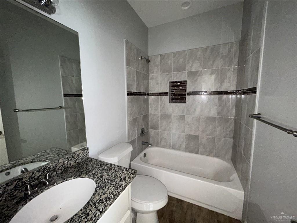 2100 Jackson Street, Unit 1 Weslaco, TX 78599 - Photo 11 of 13 a bathroom with a granite countertop bathtub shower sink vanity and toilet