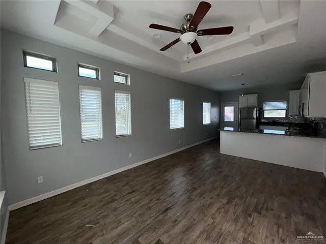 a view of an empty room with a window and wooden floor