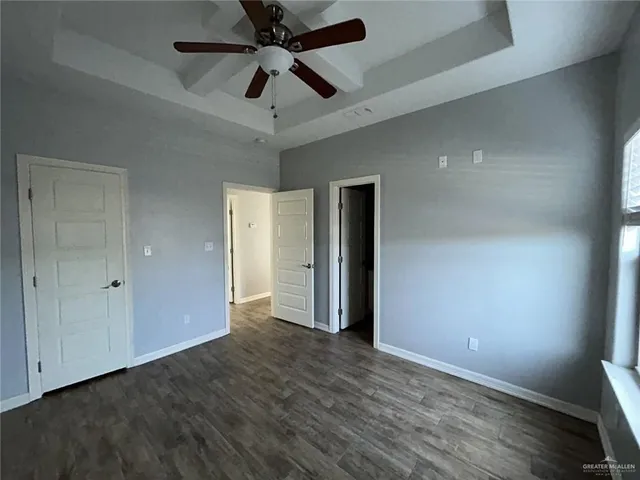 an empty room with wooden floor and a ceiling fan