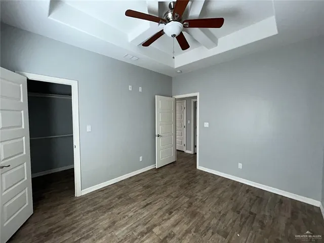 an empty room with closet and a ceiling fan