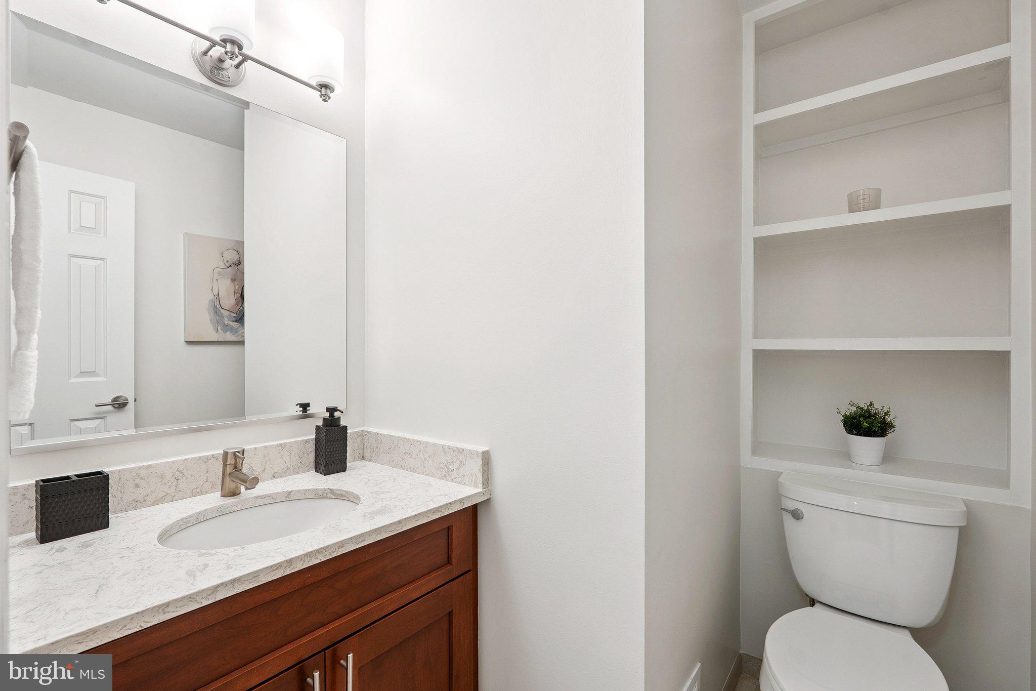 6861 Washington Boulevard Arlington, VA 22213 - Photo 12 of 28 a bathroom with a granite countertop toilet sink and a mirror