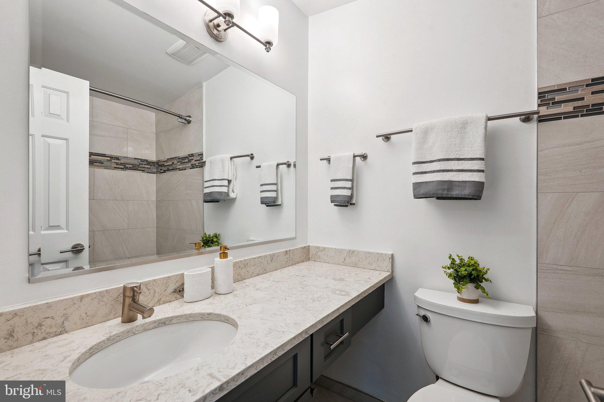 6861 Washington Boulevard Arlington, VA 22213 - Photo 20 of 28 a bathroom with a granite countertop sink a toilet a mirror and shower