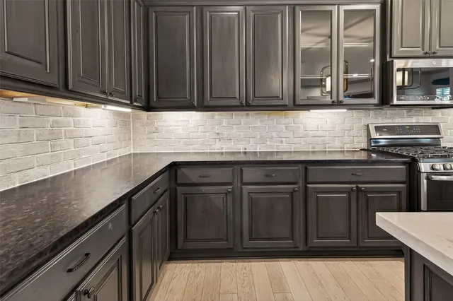 a kitchen with stainless steel appliances granite countertop a sink a stove and a microwave oven with cabinets