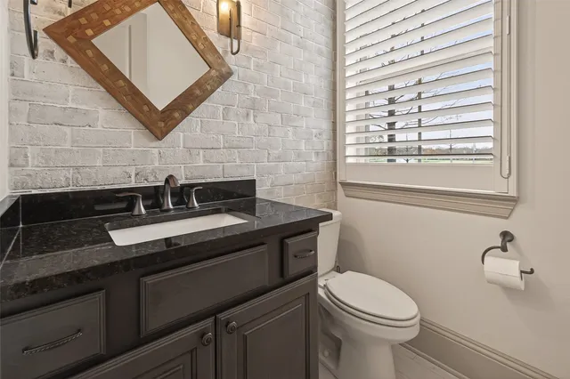 a bathroom with a granite countertop sink toilet and mirror