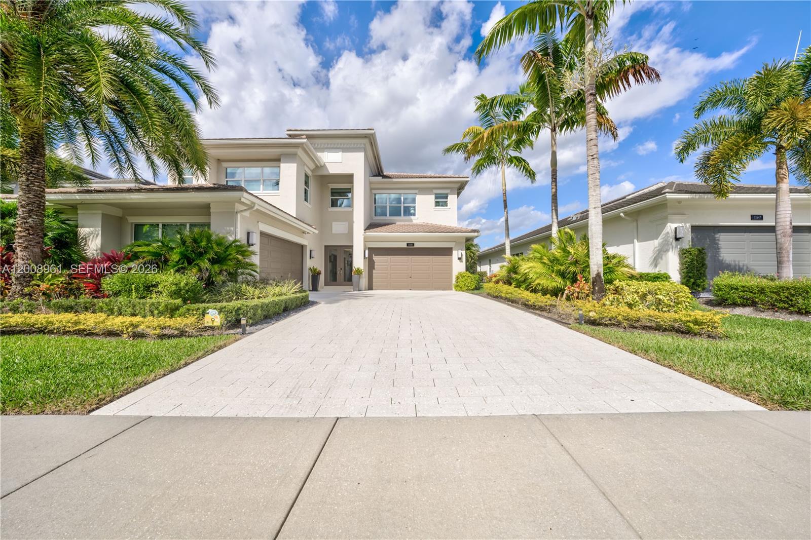 a front view of a house with a garden and palm trees