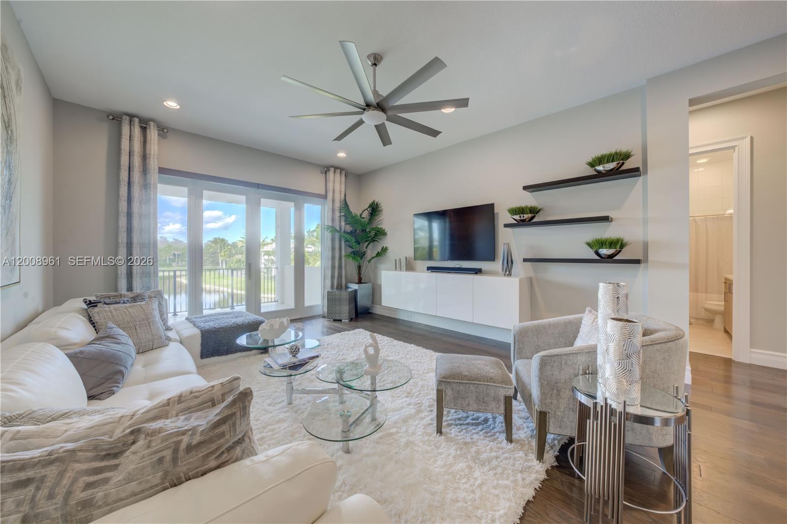 11655 Windy Frst Way Boca Raton, FL 33498 - Photo 27 of 47 a living room with furniture a flat screen tv and a floor to ceiling window