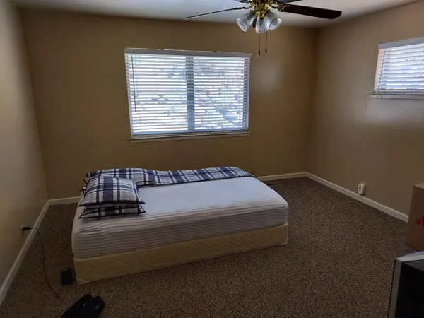 an empty room with a window and a fan