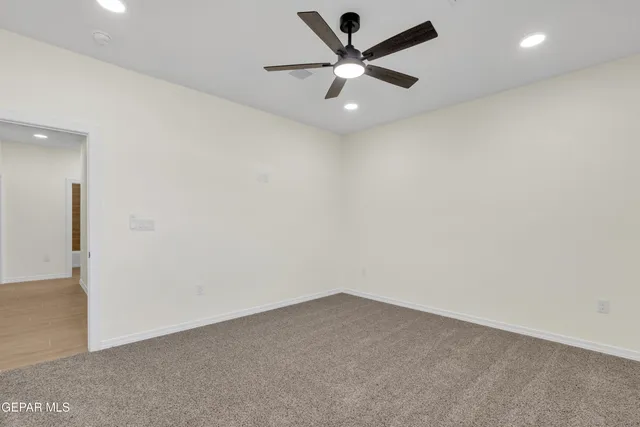 an empty room with a ceiling fan and window