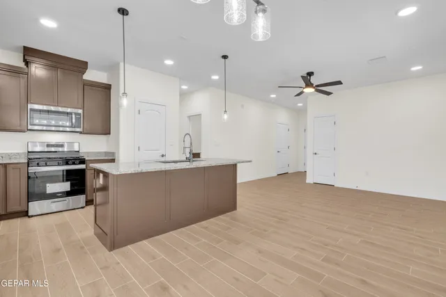 a view of kitchen with stainless steel appliances kitchen island a stove a refrigerator a sink dishwasher with a dining table and chairs