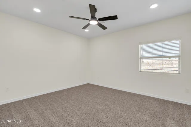 an empty room with a window and a ceiling fan