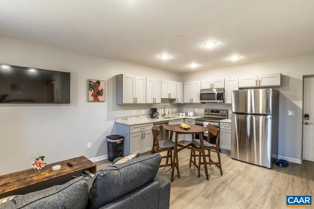 a living room with stainless steel appliances furniture and a flat screen tv