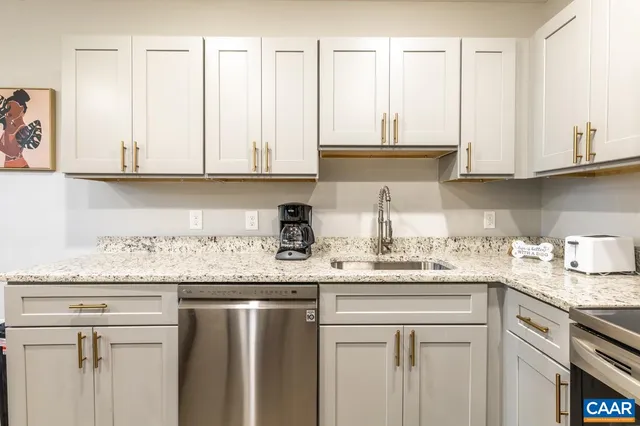 a kitchen with granite countertop stainless steel appliances white cabinets and a sink