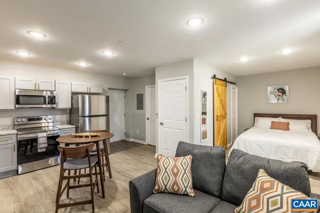 a living room with stainless steel appliances furniture and a view of kitchen