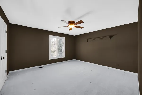 an empty room with windows and ceiling fan