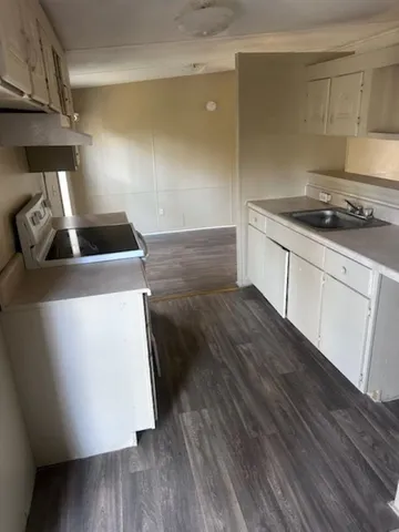 a kitchen with wooden floor sink and stove