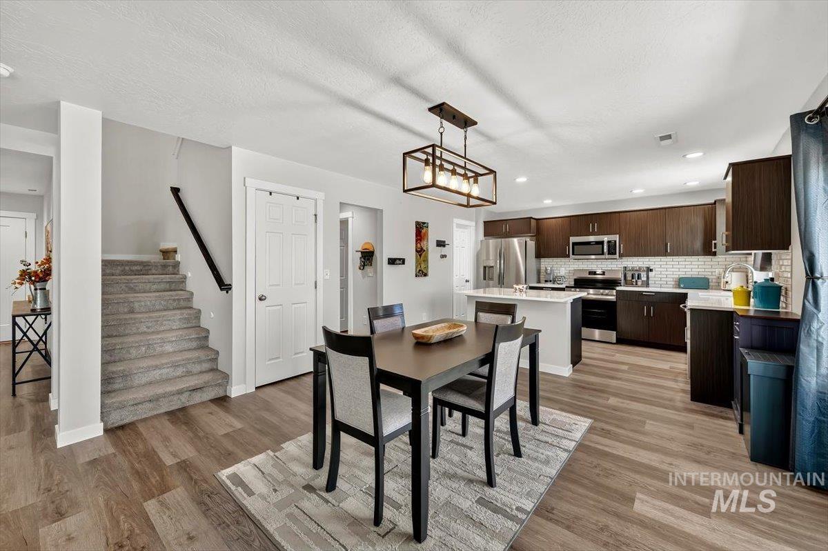 8575 South Foraker Way Kuna, ID 83634 - Photo 11 of 43 Open-concept kitchen and dining area featuring LVP flooring, recessed lighting, and a kitchen island with seating