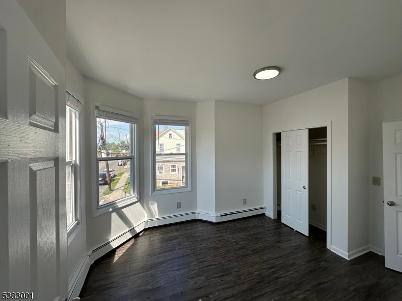 145 Smith Street, Unit 2F Elizabeth, NJ 07201 - Photo 5 of 17 an empty room with wooden floor and windows