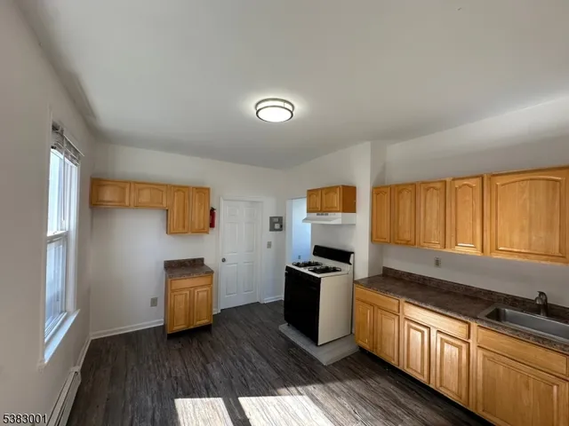 a kitchen with granite countertop a refrigerator stove top oven and sink