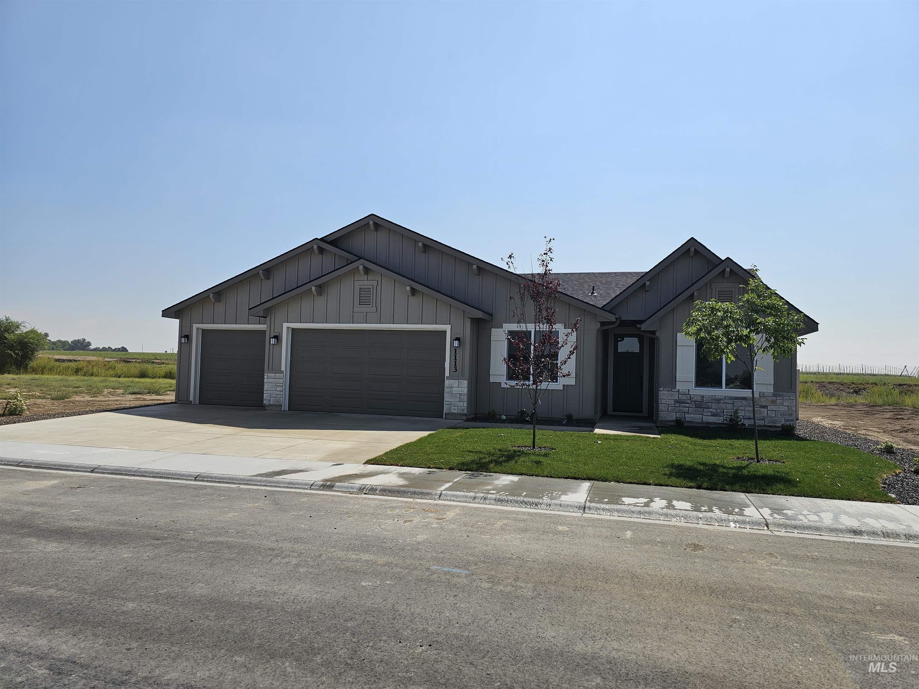 1113 Velvet Loop Wilder, ID 83676 - Photo 1 of 29 View of front of home featuring board and batten siding, driveway, stone siding, and a garage