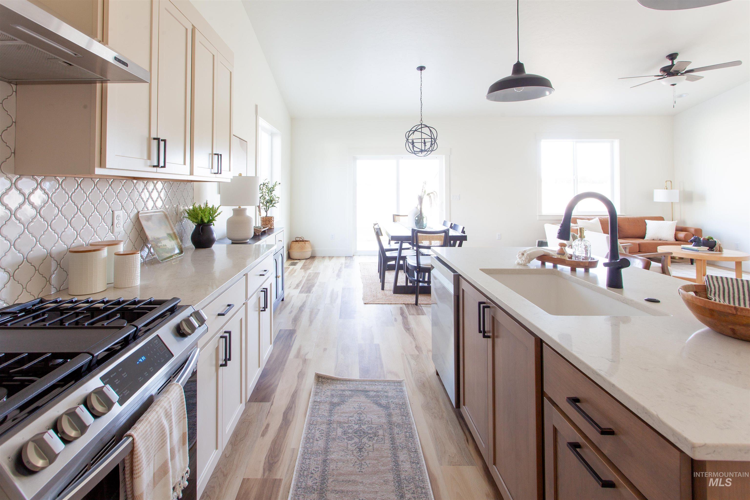1113 Velvet Loop Wilder, ID 83676 - Photo 12 of 29 Kitchen with stainless steel appliances, under cabinet range hood, decorative backsplash, light stone counters, and light wood-style floors