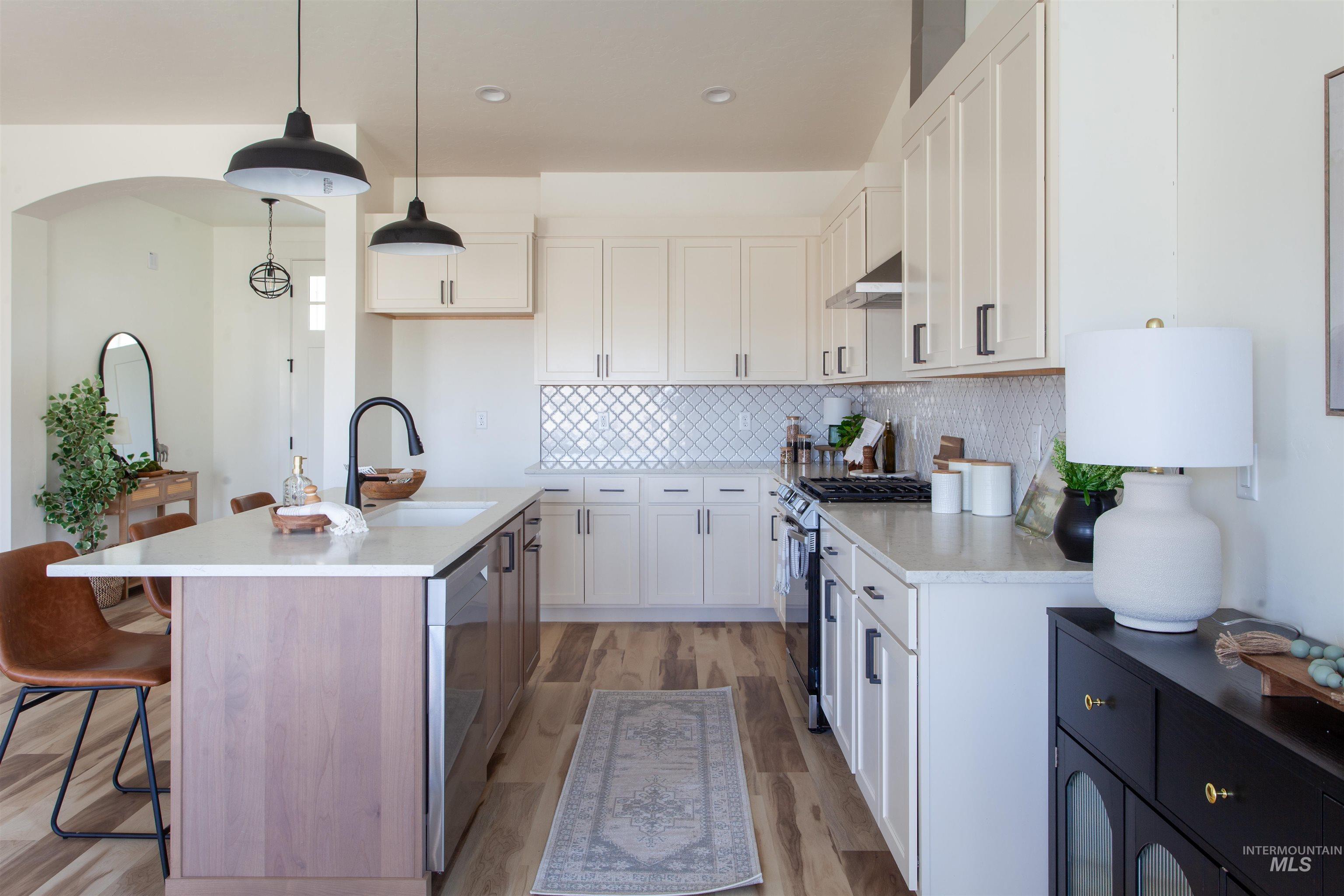 1113 Velvet Loop Wilder, ID 83676 - Photo 16 of 29 Kitchen featuring a breakfast bar area, appliances with stainless steel finishes, tasteful backsplash, white cabinets, and pendant lighting