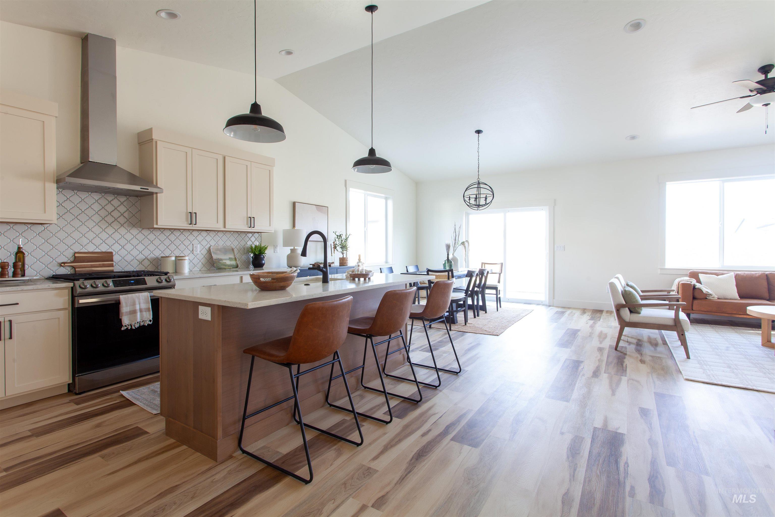 1113 Velvet Loop Wilder, ID 83676 - Photo 20 of 29 Kitchen with stainless steel gas range, pendant lighting, wall chimney range hood, tasteful backsplash, and high vaulted ceiling