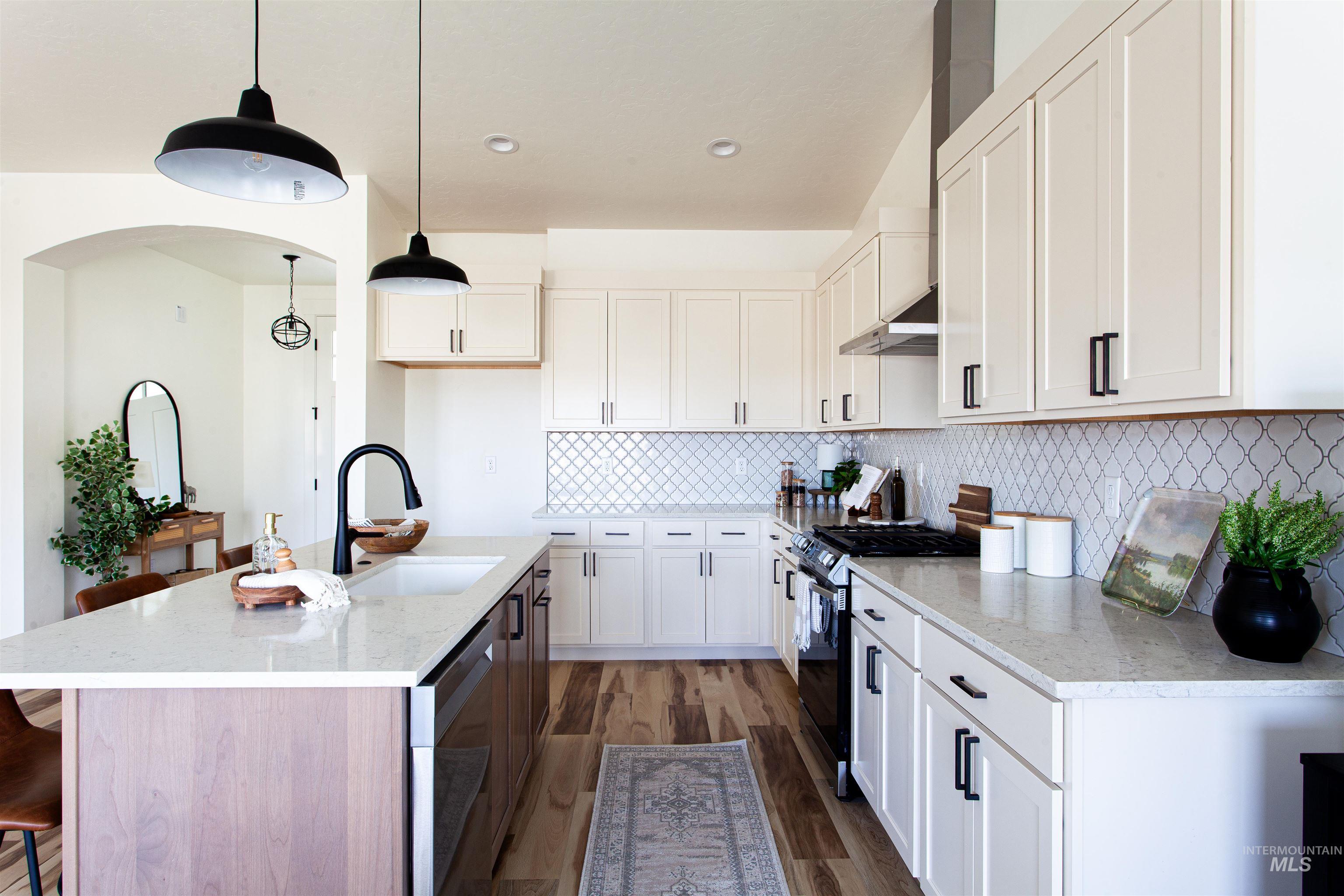 1113 Velvet Loop Wilder, ID 83676 - Photo 8 of 29 Kitchen with a kitchen breakfast bar, gas range, wall chimney range hood, dark wood-type flooring, and pendant lighting
