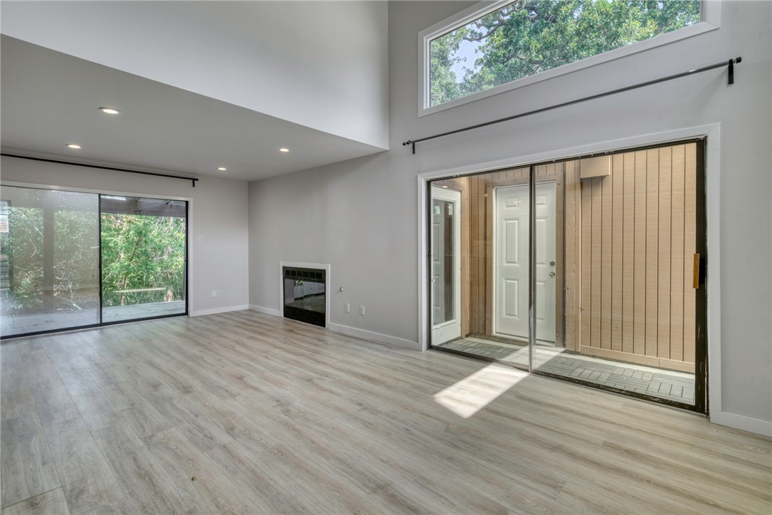 1513 Wolf Run College Station, TX 77840 - Photo 7 of 33 Unfurnished living room with a towering ceiling, recessed lighting, light wood-style flooring, and a glass covered fireplace