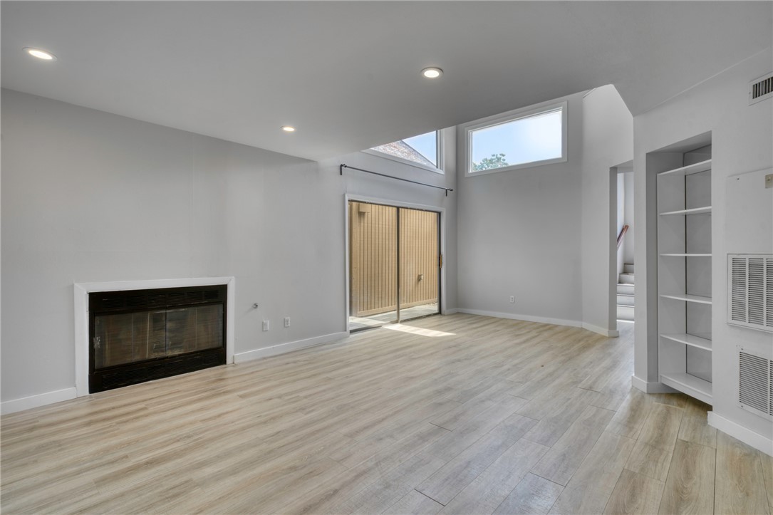 1513 Wolf Run College Station, TX 77840 - Photo 9 of 33 Unfurnished living room with a glass covered fireplace, stairs, light wood-type flooring, recessed lighting, and built in shelves