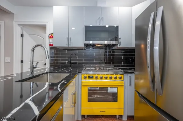 a kitchen with stainless steel appliances granite countertop a sink and a refrigerator