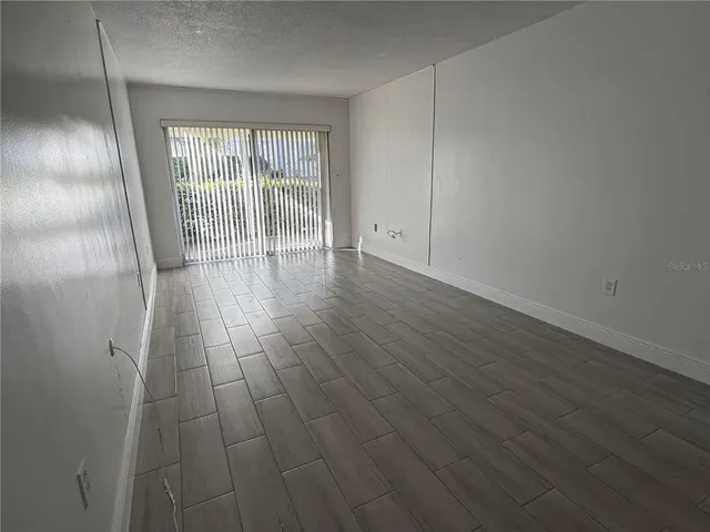 a view of an empty room with wooden floor and closet