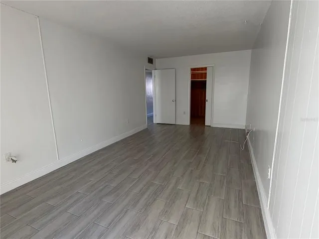 a view of an empty room with wooden floor and closet
