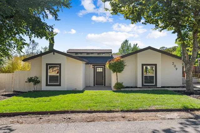 a view of a house with a yard and large tree