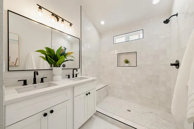 a bathroom with a sink a mirror a potted plant and a shower