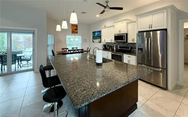 a kitchen with stainless steel appliances granite countertop a refrigerator a stove top oven a sink a dining table and chairs