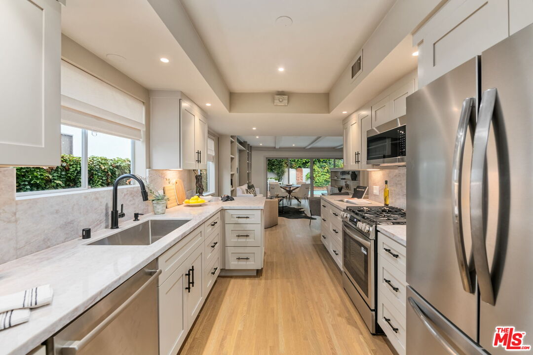 15115 Gilmore Street Van Nuys, CA 91411 - Photo 14 of 26 a kitchen with stainless steel appliances a sink stove and refrigerator